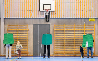 People prepare to cast their vote for Sweden’s general election in a booth at a polling station in Nacka on September 13, 2026. (Jonathan NACKSTRAND/AFP)