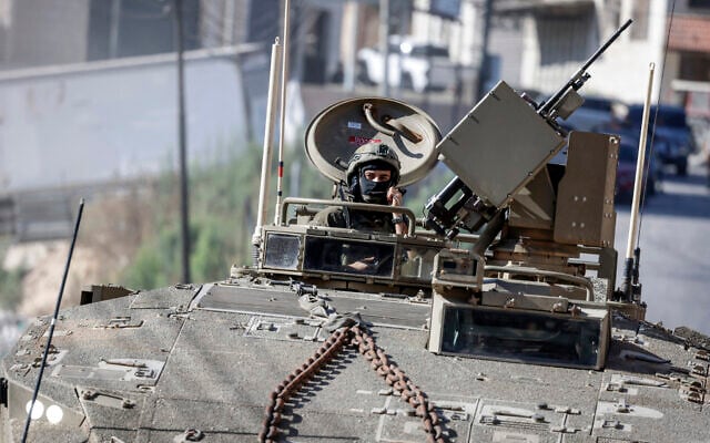 An IDF soldier sits in the hatch of an armored personnel carrier deployed during a military operation at the entrance of the Ain camp for Palestinians, west of Nablus in the West Bank, on September 17, 2026. (Zain JAAFAR/AFP)