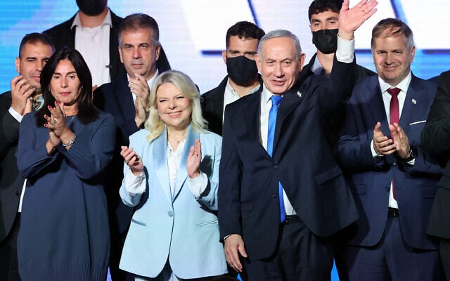 Prime Minister Benjamin Netanyahu waves next to his wife Sara as they stand on stage with Likud party lawmakers and members of the government during a Jewish New Year greetings event in Tel Aviv on September 17, 2026. (Jack GUEZ/AFP)