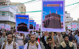Supporters of the Houthis march as they hold placards showing the Kaaba reading 'For it, we willingly offer our souls' during a protest against the Saudi intervention in Yemen and against Saudi Arabia’s recent accusation that the Houthis fired at the holy city of Mecca, in Yemen’s western Red Sea city of Hodeida on September 18, 2026. (Zayed Al-Waqidi/AFP)