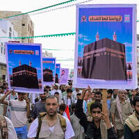Supporters of the Houthis march as they hold placards showing the Kaaba reading 'For it, we willingly offer our souls' during a protest against the Saudi intervention in Yemen and against Saudi Arabia’s recent accusation that the Houthis fired at the holy city of Mecca, in Yemen’s western Red Sea city of Hodeida on September 18, 2026. (Zayed Al-Waqidi/AFP)