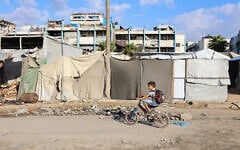 Illustrative: A Palestinian boy rides his bike past makeshift shelters on his way to school as the academic year begins in Gaza City, in the Strip's north, on September 19, 2026. (Omar AL-QATTAA/AFP)
