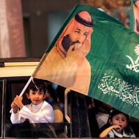 A child waves a flag bearing the image of Saudi Arabia’s Crown Price Mohammed bin Salman from a vehicle during the 96th Saudi National day celebrations in Riyadh on September 23, 2026. (Fayez NURELDINE/AFP)
