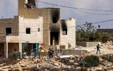 Israeli settlers and security forces are seen near a fire-damaged home in Jalud, south of Nablus in the West Bank, on September 29, 2026. (Zain JAAFAR/AFP)