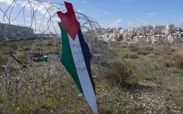 Illustrative: A placard in the shape of Israel with the colors of the Palestinian flag, and Arabic that reads 'Jerusalem is the eternal capital of Palestine,' at a barbed wire surrounding the Israeli security barrier, with the Israeli settlement of Mod’in Ilit in the background, during a protest against Israel and the US in the West Bank village of Bil’in, near Ramallah, January 31, 2020. (AP Photo/Nasser Nasser)