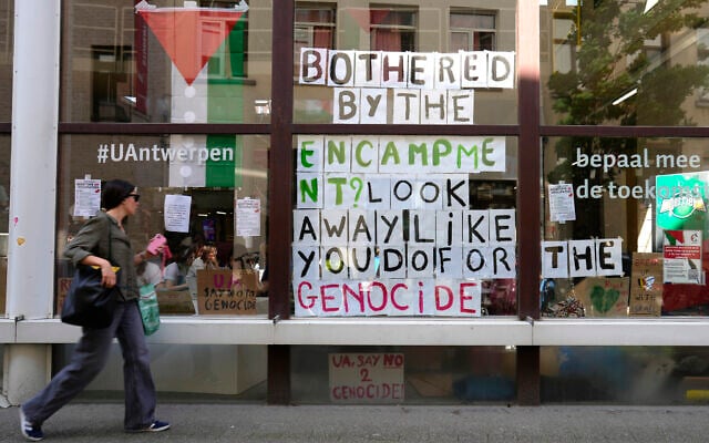A woman walks by signs hanging in a window inside of a school building at the University of Antwerp, as pro-Palestinian students occupy parts of the campus in Antwerp, Belgium, May 14, 2024. (AP/Virginia Mayo)