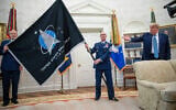 US Gen. John “Jay” Raymond, Commander US Space Command, left, and Chief Master Sgt. Roger Towberman, center, hold the Space Force Flag as President Donald Trump gestures to it during the presentation of the in the Oval Office of the White House in Washington on May 15, 2020. (AP Photo/Alex Brandon)