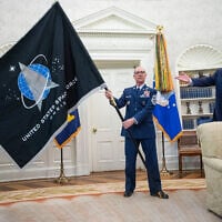US Gen. John “Jay” Raymond, Commander US Space Command, left, and Chief Master Sgt. Roger Towberman, center, hold the Space Force Flag as President Donald Trump gestures to it during the presentation of the in the Oval Office of the White House in Washington on May 15, 2020. (AP Photo/Alex Brandon)