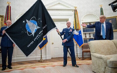 US Gen. John “Jay” Raymond, Commander US Space Command, left, and Chief Master Sgt. Roger Towberman, center, hold the Space Force Flag as President Donald Trump gestures to it during the presentation of the in the Oval Office of the White House in Washington on May 15, 2020. (AP Photo/Alex Brandon)