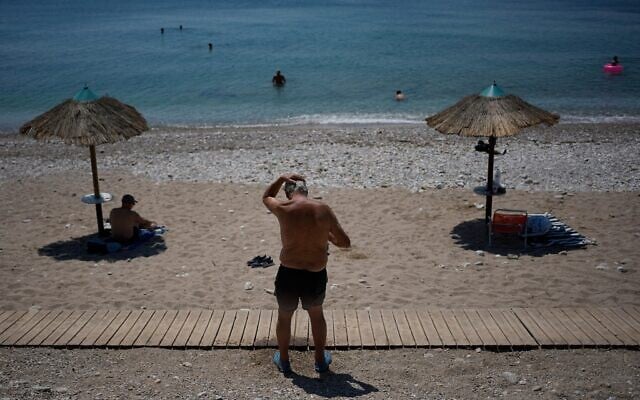 A man cools himself with water on Flisvos Beach during a heat wave in Athens, Greece, August 24, 2026. (AP Photo/Thanassis Stavrakis)