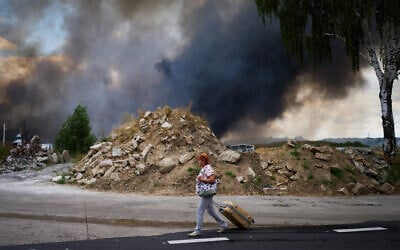 A woman walks along a road as smoke rises from a destroyed warehouse after a Russian drone attack on the outskirts of Kyiv, Ukraine, August 27, 2026. (AP Photo/Francisco Seco) A woman walks along a road as smoke rises from a destroyed warehouse after a Russian drone attack on the outskirts of Kyiv, Ukraine, August 27, 2026. (AP Photo/Francisco Seco)