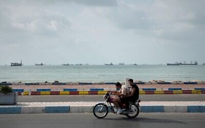 Two men ride a motorcycle along the waterfront as commercial vessels lie anchored in the Strait of Hormuz off Bandar Abbas, Iran, September 4, 2026. (AP Photo/Vahid Salemi)