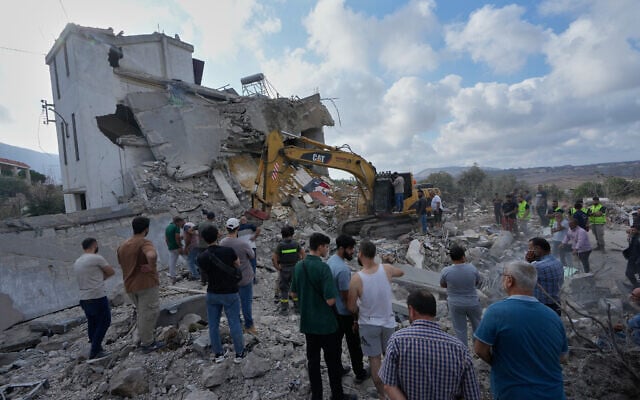 People watch rescue workers use an excavator as they conduct a search operation at a destroyed house that was hit by an Israeli airstrike after an evacuation warning in Arab Salim village, southern Lebanon, September 6, 2026. (AP Photo/Mohammed Zaatari)
