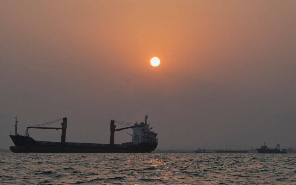 The sun sets over commercial vessels anchored in the Strait of Hormuz off Bandar Abbas, Iran, with the city’s skyline in the background, September 6, 2026. (AP/Vahid Salemi)
