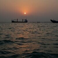The sun sets over commercial vessels anchored in the Strait of Hormuz off Bandar Abbas, Iran, with the city’s skyline in the background, September 6, 2026. (AP Photo/Vahid Salemi)