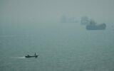 A motorboat travels past commercial vessels anchored amid haze in the Strait of Hormuz off Bandar Abbas, Iran, September 7, 2026. (AP Photo/Vahid Salemi)