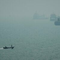 A motorboat travels past commercial vessels anchored amid haze in the Strait of Hormuz off Bandar Abbas, Iran, September 7, 2026. (AP Photo/Vahid Salemi)