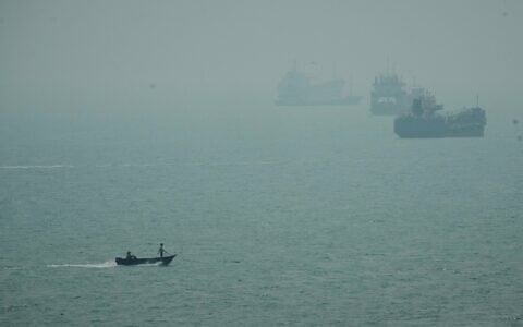 A motorboat travels past commercial vessels anchored amid haze in the Strait of Hormuz off Bandar Abbas, Iran, September 7, 2026. (AP Photo/Vahid Salemi)