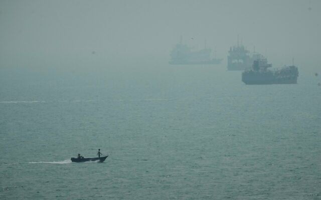 A motorboat travels past commercial vessels anchored amid haze in the Strait of Hormuz off Bandar Abbas, Iran, September 7, 2026. (AP Photo/Vahid Salemi)