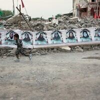 A child runs past a banner strung across the rubble of the Shajareh Tayyebeh school showing portraits of the children and teachers killed there by a February 28 US airstrike in Minab, southern Iran, September 7, 2026. (AP/Vahid Salemi)