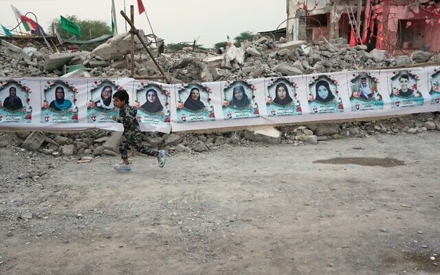 A child runs past a banner strung across the rubble of the Shajareh Tayyebeh school showing portraits of the children and teachers killed there by a February 28 US airstrike in Minab, southern Iran, September 7, 2026. (AP/Vahid Salemi)