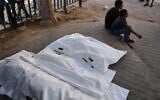 Palestinians sit beside the bodies of people killed in an Israeli strike, at Shifa Hospital in Gaza City, September 10, 2026. (AP/Jehad Alshrafi)
