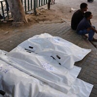 Palestinians sit beside the bodies of people killed in an Israeli strike, at Shifa Hospital in Gaza City, September 10, 2026. (AP/Jehad Alshrafi)