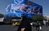 Pedestrian walk past a billboard depicting a Persian legendary hero and flying figure hitting US aircraft carriers at Islamic Revolution square in downtown Tehran, Iran, September 14, 2026. (AP Photo/Vahid Salemi)