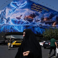 Pedestrian walk past a billboard depicting a Persian legendary hero and flying figure hitting US aircraft carriers at Islamic Revolution square in downtown Tehran, Iran, September 14, 2026. (AP Photo/Vahid Salemi)
