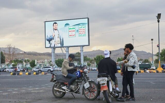 Young men gather beneath a billboard depicting Houthi leader Abdul-Malik al-Houthi in Sanaa, Yemen, September 15, 2026. (AP Photo/Osamah Abdulrahman)