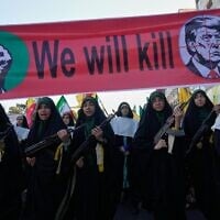 Women affiliated with Iran’s Islamic Revolutionary Guard Corps carry rifles as they march beneath a banner depicting US President Donald Trump in crosshairs and reading “We will kill” during the state-organized “Janfada,” or “Sacrifice for Iran,” military-style parade in Tehran, Iran, September 18, 2026. (AP Photo/Vahid Salemi)