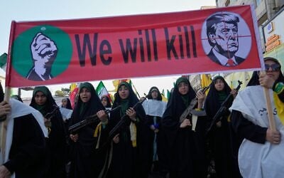 Women affiliated with Iran’s Islamic Revolutionary Guard Corps carry rifles as they march beneath a banner depicting US President Donald Trump in crosshairs and reading 'We will kill' during the state-organized 'Janfada,' or 'Sacrifice for Iran,' military-style parade in Tehran, Iran, September 18, 2026. (AP Photo/Vahid Salemi)