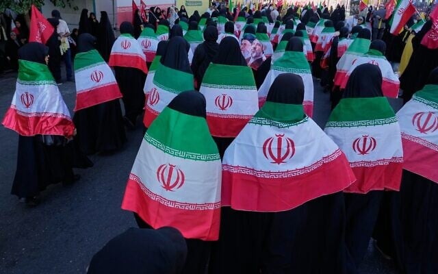 Women draped in Iranian flags march during the state-organized 'Janfada,' or 'Sacrifice for Iran,' military-style parade in Tehran, Iran, on September 18, 2026. (AP Photo/Vahid Salemi)