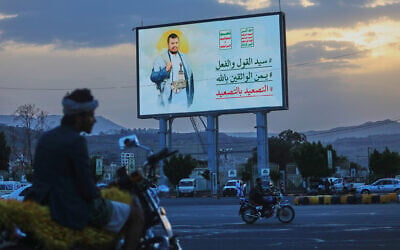 People ride their motorbikes under a billboard showing Houthi leader Abdul Malik al-Houthi with a phrase that reads, in Arabic; “master of words and deeds,” in Sanaa, Yemen, September 21, 2026. (AP Photo/Osamah Abdulrahman)