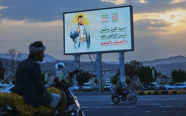 People ride their motorbikes under a billboard showing Houthi leader Abdul Malik al-Houthi with a phrase that reads, in Arabic; “master of words and deeds,” in Sanaa, Yemen, September 21, 2026. (AP Photo/Osamah Abdulrahman)