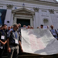 Priests from various countries, members of the “Priests Against Genocide” network, carry a shroud bearing the names of 300 Palestinian and Lebanese children whom organizers say were killed by the Israeli military after ceasefires were declared, during a demonstration near St. Peter’s Square at the Vatican, September 22, 2026. (AP Photo/Gregorio Borgia)