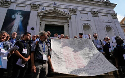 Priests from various countries, members of the “Priests Against Genocide” network, carry a shroud bearing the names of 300 Palestinian and Lebanese children whom organizers say were killed by the Israeli military after ceasefires were declared, during a demonstration near St. Peter’s Square at the Vatican, September 22, 2026. (AP Photo/Gregorio Borgia)