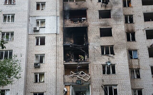 A police officer throws fragments of a Shahed drone from the balcony of a house damaged in a Russian strike on a residential neighborhood in Kyiv, Ukraine, September 25, 2026. (AP Photo/Evgeniy Maloletka)