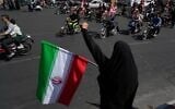 A woman chants slogan as she holds an Iranian flag while motorcyclists ride during a state-organized motorcycle parade called 'Janfada,' meaning 'Sacrifice for Iran,' in Tehran, Iran, September 25, 2026. (AP Photo/Vahid Salemi)