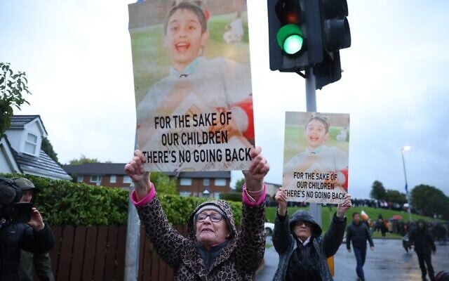 Protesters hold banners ahead of a Portadown District Loyal Orange Lodge (LOL) No 1 march in the first parade for almost 30 years, after the parade was given clearance in a late-night hearing, in Portadown, Northern Ireland, September 27, 2026. (Peter Morrison/PA via AP)