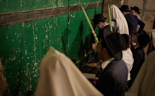 Orthodox Jewish men pray in front of the gate at Souq Al-Qattanin, or Cotton Merchants’ Market, one of the entrances to the Al-Aqsa Mosque compound in the Old City of Jerusalem, September 28, 2026, during morning prayers for the Jewish holiday of Sukkot. (AP Photo/Leo Correa)