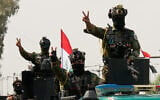 Iraqi security officers flash victory signs while riding in vehicles decorated with national flags during a convoy celebrating the complete withdrawal of US troops from Iraq, in Baghdad, Iraq, September 30, 2026. (AP Photo/Hadi Mizban)