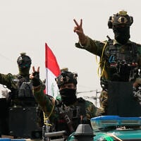 Iraqi security officers flash victory signs while riding in vehicles decorated with national flags during a convoy celebrating the complete withdrawal of US troops from Iraq, in Baghdad, Iraq, September 30, 2026. (AP Photo/Hadi Mizban)