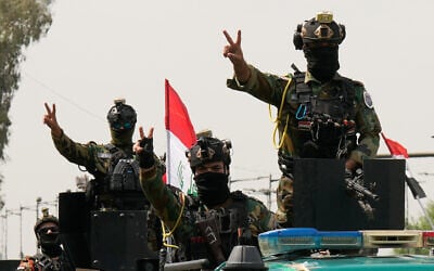 Iraqi security officers flash victory signs while riding in vehicles decorated with national flags during a convoy celebrating the complete withdrawal of US troops from Iraq, in Baghdad, Iraq, September 30, 2026. (AP Photo/Hadi Mizban)