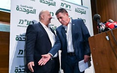 Yoav Segalovitz, right, reaches for the hand of Ra'am leader Mansour Abbas at a press conference in Nazareth on August 31, 2026. (Michael Giladi/FLASH90)