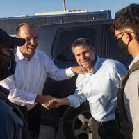 MK Simcha Rothman (left) and Finance Minister Bezalel Smotrich (right), flanked by masked security personnel, arrive at a ceremony marking the establishment of the new Israeli settlement of Ma’ale Arugot in Gush Etzion, in the West Bank, September 2, 2026. (Chaim Goldberg/Flash90)