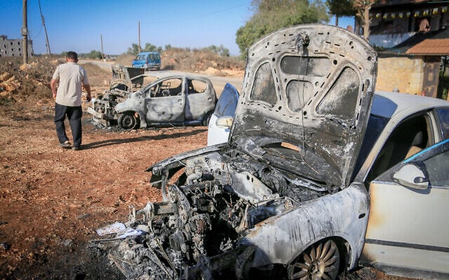 Palestinians inspect burned-out cars after an attack by settlers, where they also spray-painted
Hebrew graffiti on the walls of a house in Beita, south of Nablus in the West Bank. September 2, 2026. (Nasser
Ishtayeh/Flash90)