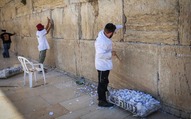 Workers remove handwritten prayer notes placed between the ancient stones of the Western Wall in Jerusalem’s Old City, September 6, 2026. (Flash90)