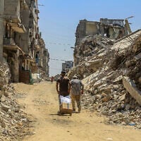 Palestinians walk past destroyed buildings from the recent war in the Tel al-Hawa neighborhood of Gaza City, September 8, 2026. (Abed Rahim Khatib/Flash90)