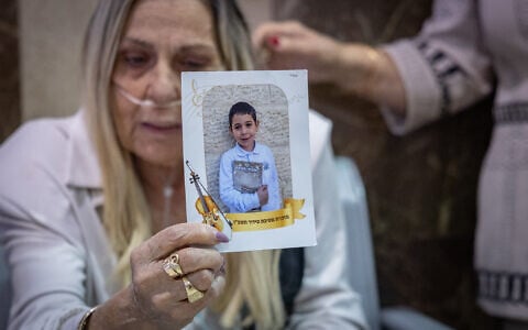 Family members of seven-year-old Hillel Mordechai Dadon, who was allegedly murdered by his neighbor, 26-year-old Liel Ifergan, hold up his picture as prosecutors filed murder charges at the Jerusalem District Court, September 14, 2026. (Yonatan Sindel/Flash90)